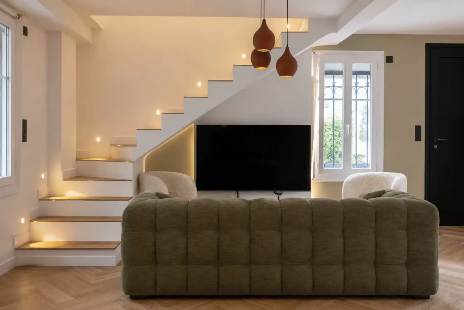 Living room with staircase and TV wall